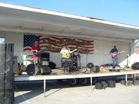 2007 Ford Mustang - A band plays music on a stage decorated with an American flag and a "God Bless America" banner.