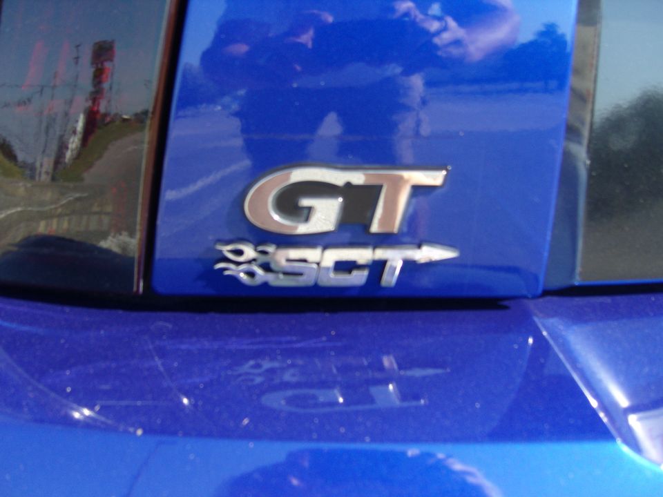Blue car's rear with GT SCT badge and reflection of a person