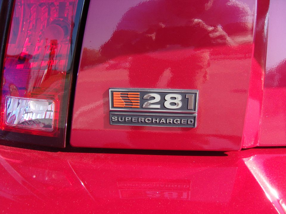 Red car rear emblem reads 281 SUPERCHARGED