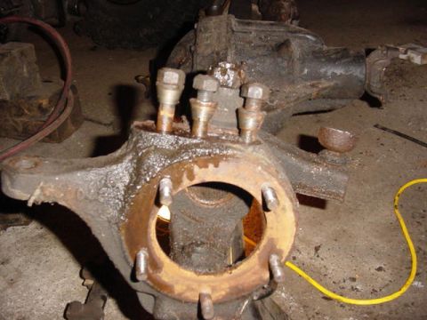 1992 Ford Bronco - Close-up of a front axle knuckle, likely from a truck or SUV, with visible studs and bolts. The Supermotors.net logo is present in the lowe…