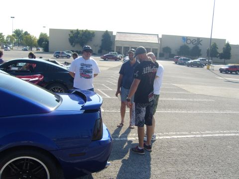 2007 Ford Mustang - A blue Ford Mustang is parked in a lot with several people gathered around.