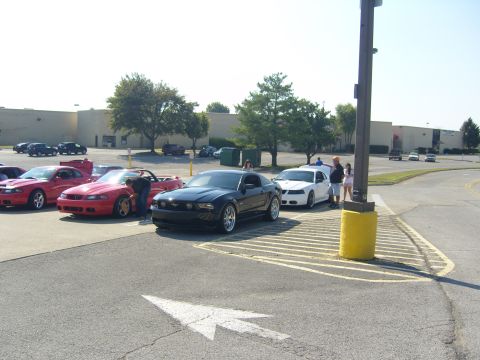 2007 Ford Mustang - A black 2007 Ford Mustang coupe is parked in a lot with other Mustangs during a car show.