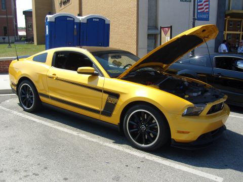 2007 Ford Mustang - A yellow Ford Mustang Boss 302 is parked with its hood open, displaying its engine bay.