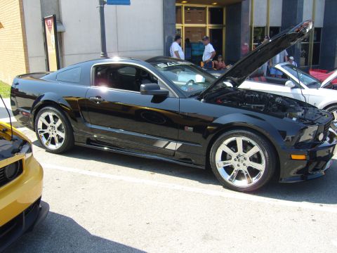 2007 Ford Mustang - A black 2007 Ford Mustang is displayed with its hood open at a car show, with another vehicle partially visible in the foreground.