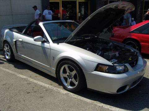 2007 Ford Mustang - Silver convertible Mustang with hood open at a car show.