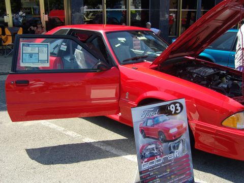 2007 Ford Mustang - A red Ford Mustang is displayed with its hood and door open, next to a sign indicating it is a 1993 Cobra R model.