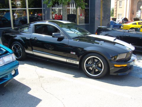 2007 Ford Mustang - A black 2007 Ford Mustang Shelby GT is parked at a car show with other vehicles visible.