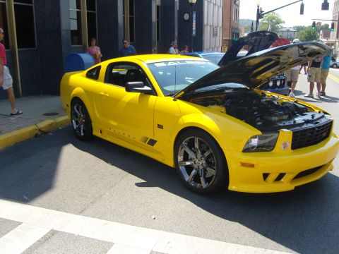 2007 Ford Mustang - A bright yellow Saleen Mustang is parked on a street with its hood open, displaying the engine.