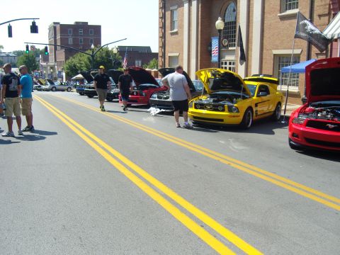 2007 Ford Mustang - Several Ford Mustangs are displayed with hoods up at a street event.