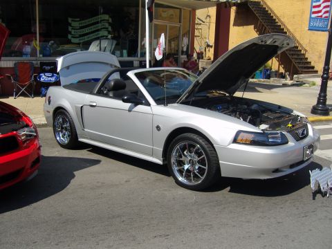 2007 Ford Mustang - A silver 2007 Ford Mustang convertible is displayed with its hood open at a car show.