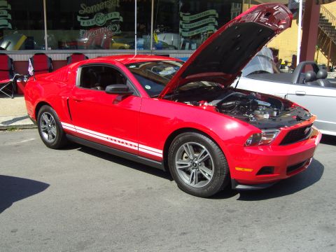 2007 Ford Mustang - Red Ford Mustang with hood open, parked on street next to another vehicle.