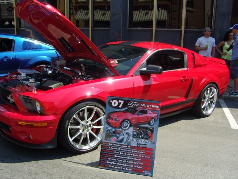 2007 Ford Mustang - A red 2007 Ford Mustang Shelby GT500 Super Snake is displayed with its hood open at a car show.