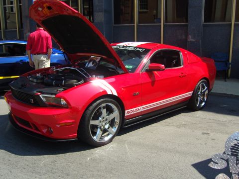 2007 Ford Mustang - A red 2007 Ford Mustang GT is displayed with its hood open, racing stripes and ROUSH branding.