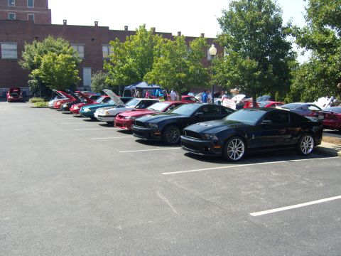2007 Ford Mustang - A line of Ford Mustangs are parked at a car show, with a black 2007 model prominently in the foreground.