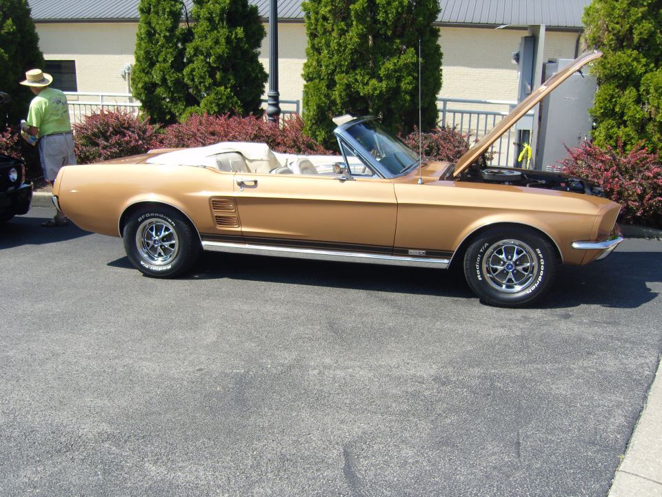 Gold 1967 Ford Mustang convertible with hood open, parked on asphalt