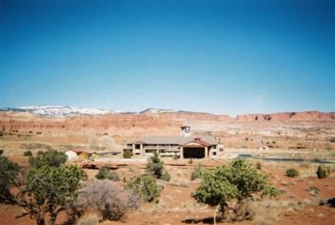 1991 Ford LTD Crown Victoria - A wide view of a desert landscape a building, red rock formations, and sparse vegetation under a clear blue sky.