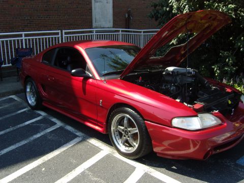 2007 Ford Mustang - A red coupe with its hood open, revealing the engine bay and aftermarket wheels.