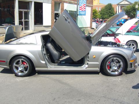 2007 Ford Mustang - A silver car with its doors and hood open at a car show.