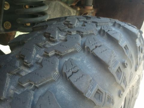 2004 Ford F-350 - The aggressive tread pattern of an off-road tire is shown in detail, with suspension parts visible overhead.