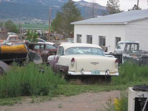 1991 Ford LTD Crown Victoria - Rear view of a 1955 Chevrolet Bel Air parked in a junkyard with other vehicles.
