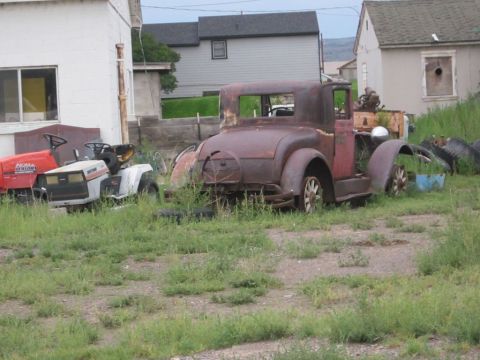 1991 Ford LTD Crown Victoria - A weathered vintage coupe sits in a grassy lot next to a riding mower.