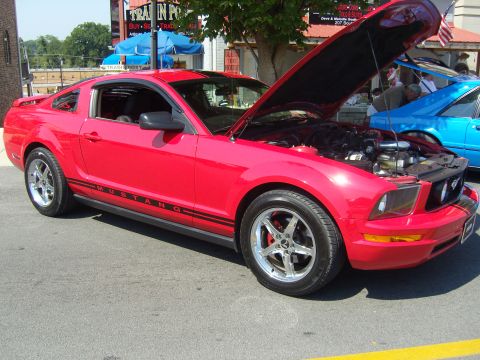 2007 Ford Mustang - A red 2007 Ford Mustang is displayed with its hood open, parked next to a blue car.