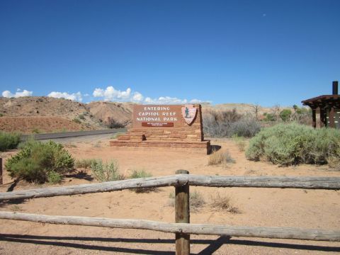 1991 Ford LTD Crown Victoria - Entering Capitol Reef National Park sign with arid vegetation and distant hills under a clear sky.
