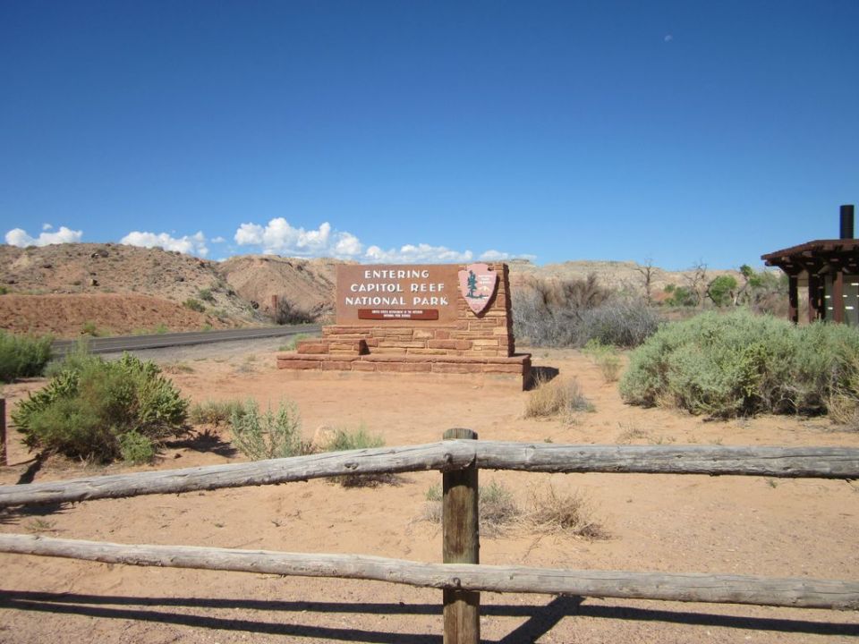 Capitol Reef National Park entrance sign with desert landscape and blue sky