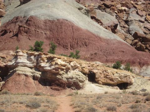 1991 Ford LTD Crown Victoria - Layered rock formations in a desert landscape with a visible dirt path and some trees.
