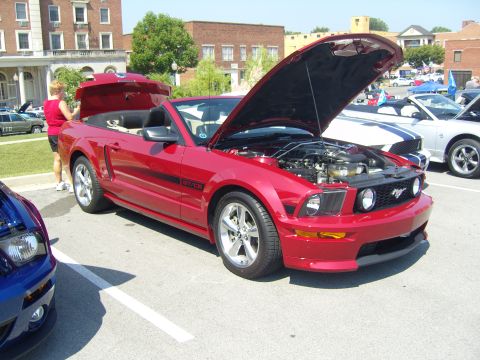 2007 Ford Mustang - Red 2007 Ford Mustang convertible at a car show, hood and trunk open, with another Mustang in the foreground.