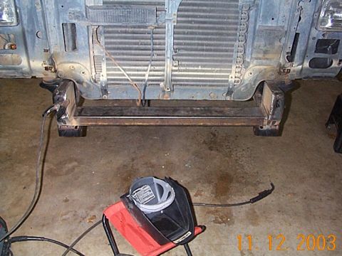1986 Ford Bronco - Welding equipment is positioned near the front frame and radiator of a vehicle undergoing modifications.