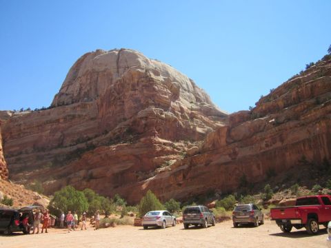 1991 Ford LTD Crown Victoria - Tourists gather near vehicles at the base of a massive, layered sandstone formation on a sunny day.