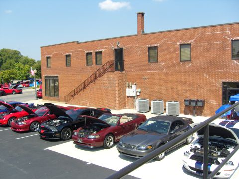 2007 Ford Mustang - A collection of Ford Mustangs are displayed with their hoods open, their engines at an outdoor event.