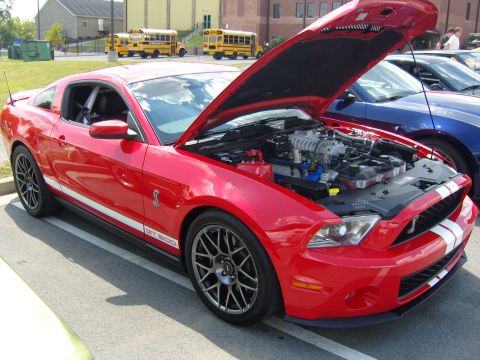 2007 Ford Mustang - A red Ford Mustang GT500 is parked with its hood open, revealing the engine compartment.