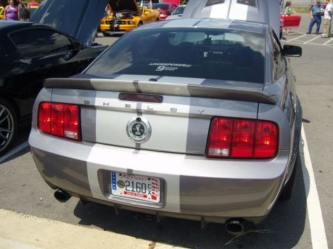 2007 Ford Mustang - A silver Ford Mustang Shelby GT500 is parked at an outdoor car show, with other vehicles visible.