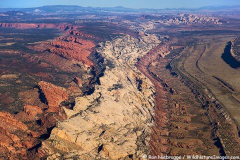 1991 Ford LTD Crown Victoria - Vast desert landscape with dramatic geological formations and a winding dry riverbed, viewed from above.