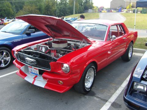 2007 Ford Mustang - A vintage red Ford Mustang is displayed with its hood open, revealing the engine compartment.