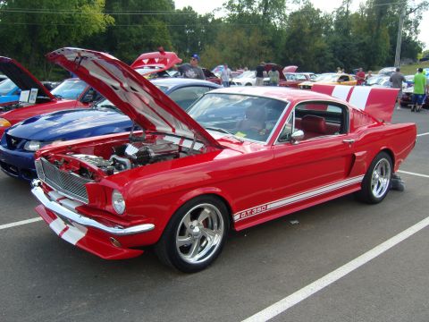 2007 Ford Mustang - A classic red 1965 Ford Mustang GT350 is displayed with its hood and trunk open at a car show.