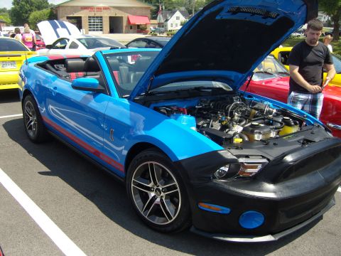 2007 Ford Mustang - A blue 2007 Ford Mustang convertible is displayed with its hood open at a car show.