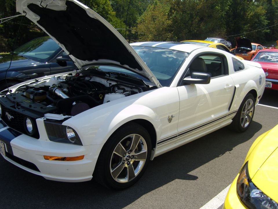 White 2007 Ford Mustang with hood open, showing engine and racing stripes