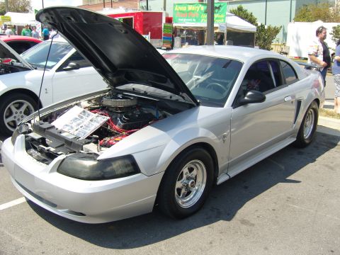 2007 Ford Mustang - Silver Ford Mustang with hood open at an outdoor car show.