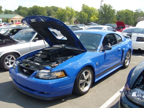 2007 Ford Mustang - A bright blue 2007 Ford Mustang is parked with its hood open at a car show.
