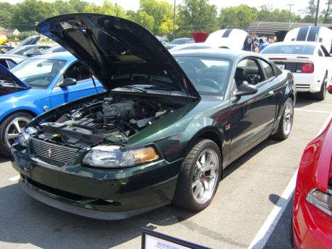 2007 Ford Mustang - Dark green Ford Mustang parked at an outdoor car show, hood open to display the engine.