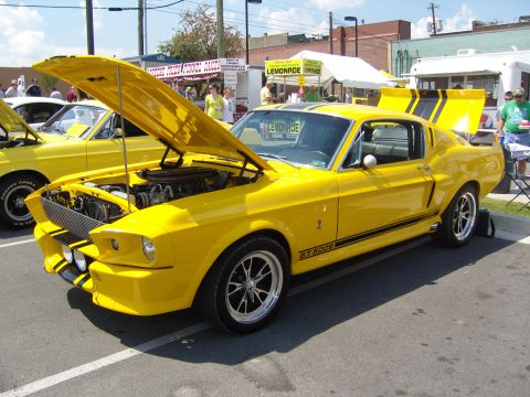 2007 Ford Mustang - A bright yellow 1967 Ford Mustang GT500 is displayed with its hood and trunk open at a car show.