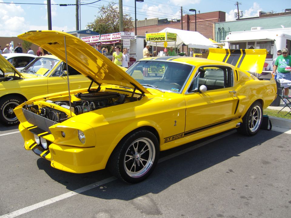 Yellow 1967 Ford Mustang GT500 with hood and trunk open, black stripes