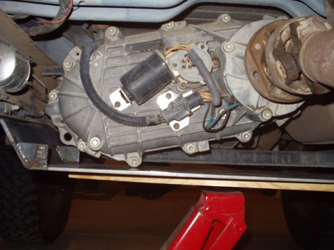 1993 Ford Bronco - Close-up of the vehicle's transfer case and part of the driveshaft, showing electrical connections and mounting hardware.