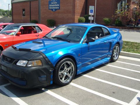 2007 Ford Mustang - A blue coupe with a car bra is parked in a lot next to a red car.