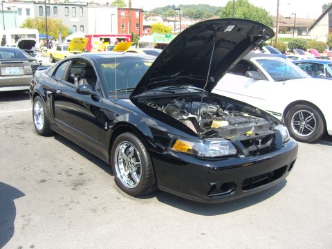 2007 Ford Mustang - A black 2007 Ford Mustang is displayed with its hood open at a car show.