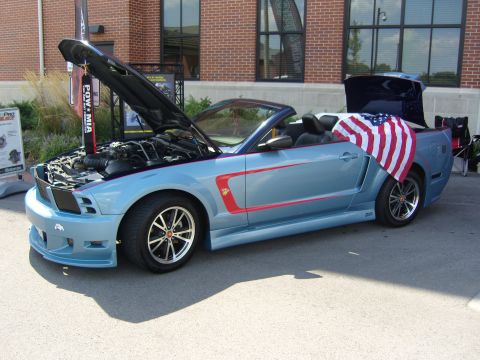 2007 Ford Mustang - Light blue convertible Mustang with red racing stripes, hood and trunk open, displaying an American flag.
