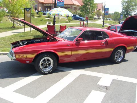 2007 Ford Mustang - A red 1969 Ford Mustang GT500 with yellow stripes is displayed at a car show.
